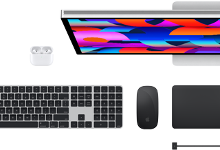 Mac-tilbehør set oppefra: Studio Display, AirPods, Magic Keyboard, Magic Mouse og Magic Trackpad